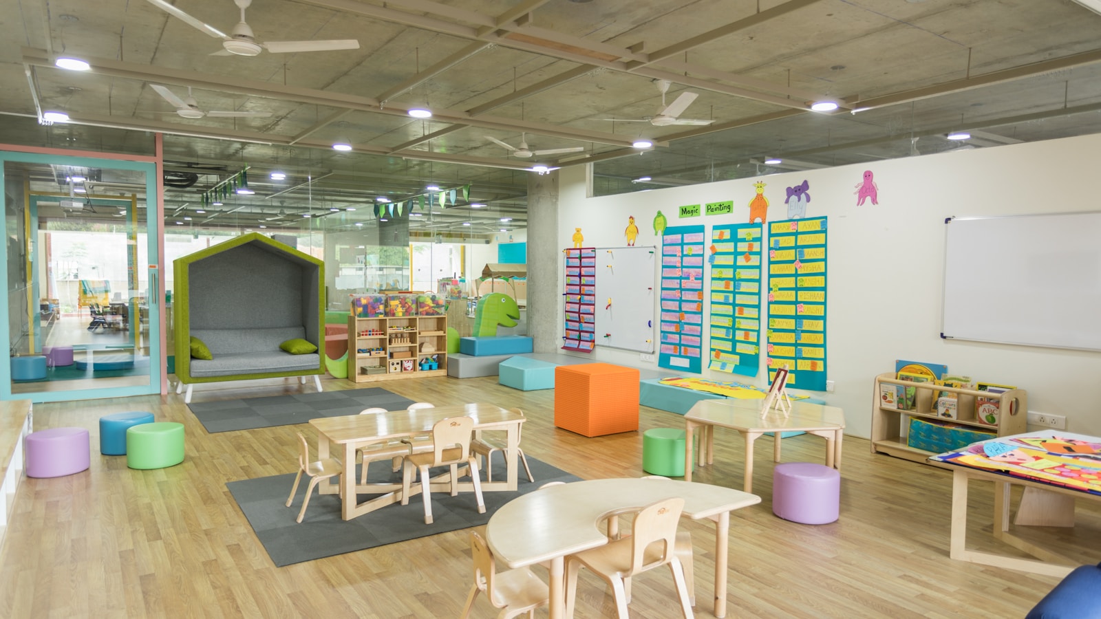 Empty daycare classroom with child-size tables, chairs, books and activity areas