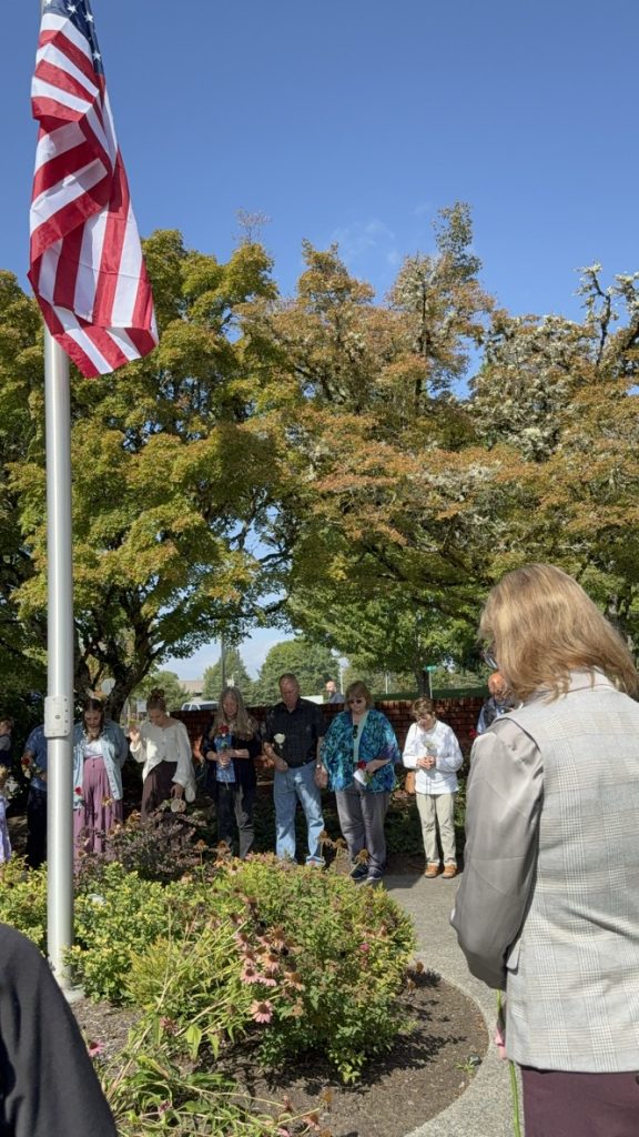 Outdoor gathering beneath an American flag