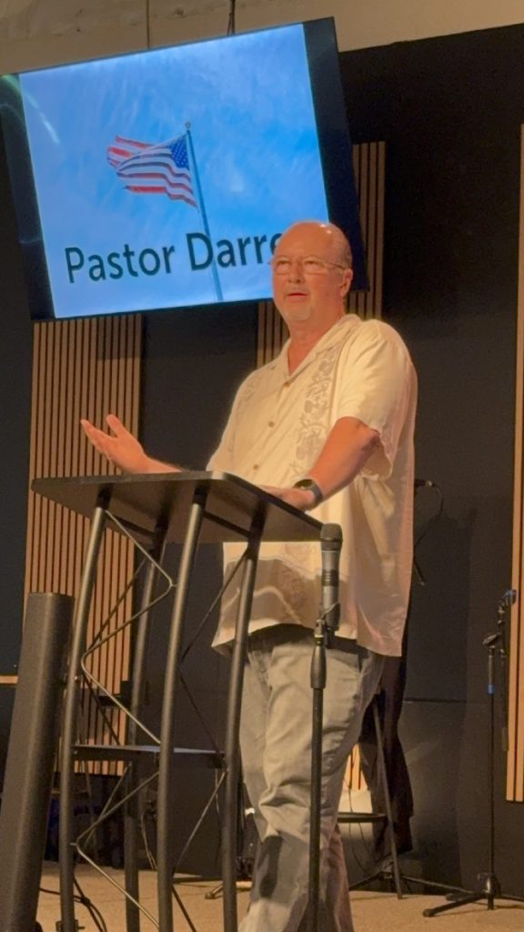Man speaking at a lectern during an indoor gathering